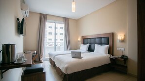 A hotel room with two beds, a desk with a laptop, a coffee maker, and a view of the outside. - Hôtel Étoile du Nord (Tangier)