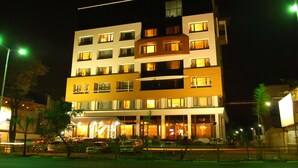 A multi-story hotel with illuminated windows and a well-lit entrance. - Hotel EEFA (Belagavi)