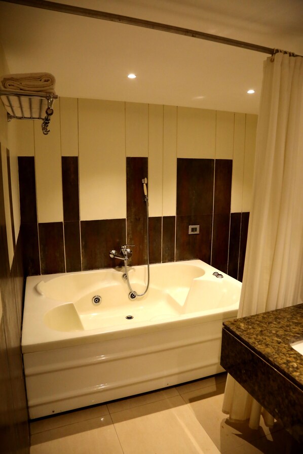 A modern bathroom with a large bathtub, a towel rack, and a marble countertop.