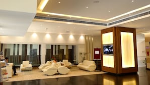 A modern lobby with plush seating, a reception desk, and a large screen displaying content. - Hotel EEFA (Belagavi)