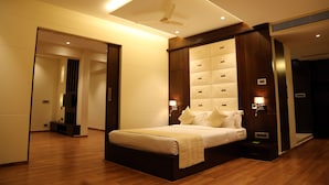 A modern hotel room with a large bed, built-in headboard, bedside lamps, and a ceiling fan. - Hotel EEFA (Belagavi)