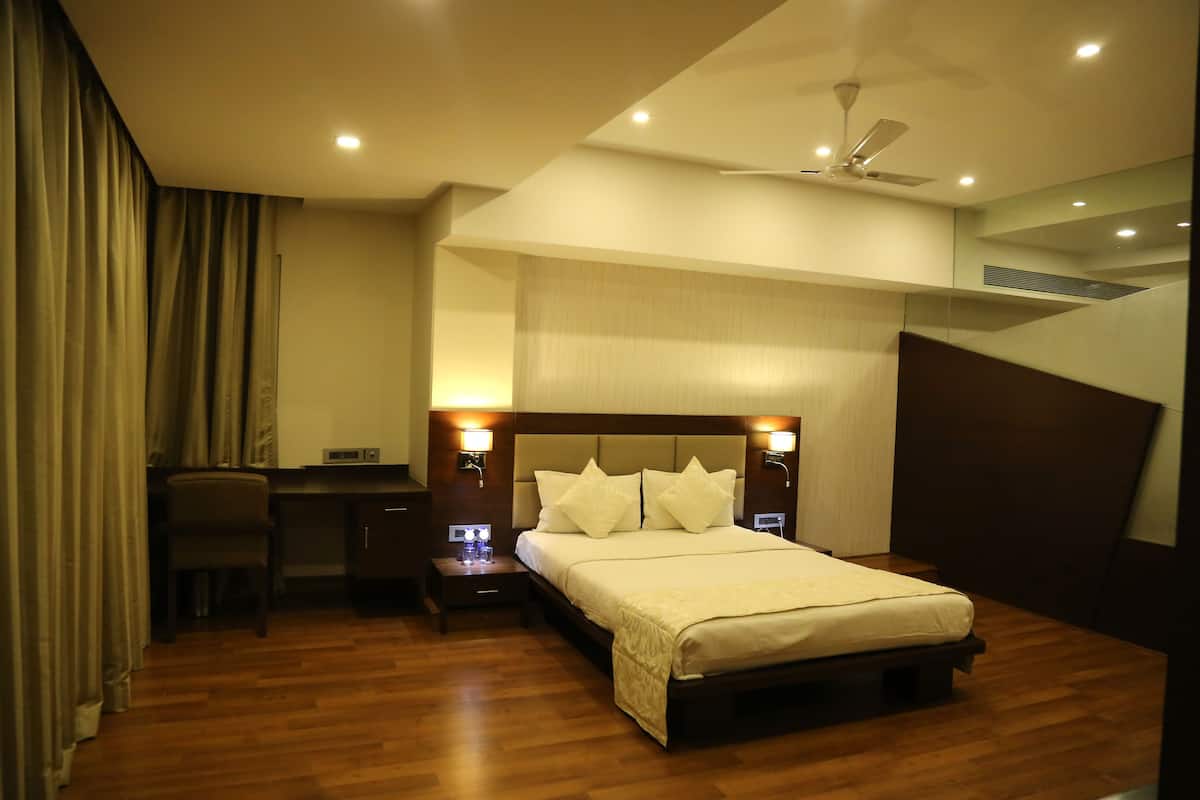 A modern hotel room with a large bed, a desk, and a chair.