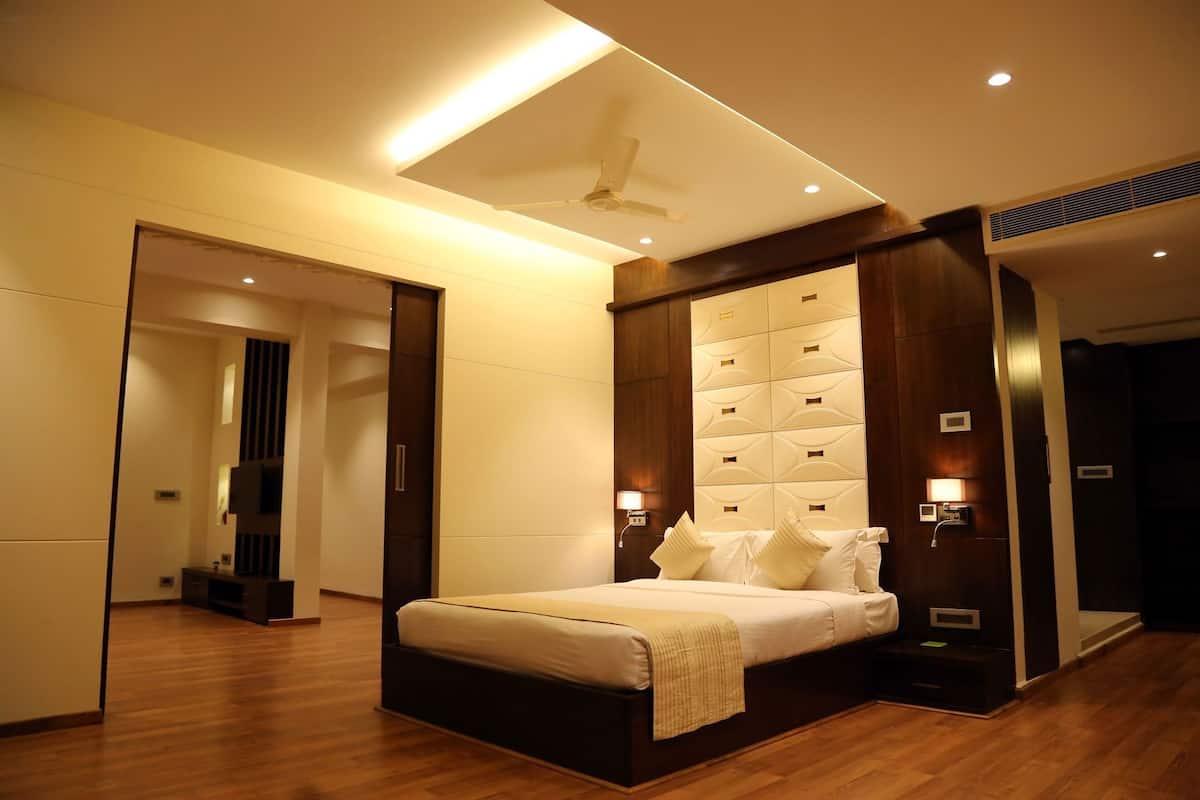 A modern hotel room with a large bed, built-in headboard, bedside lamps, and a ceiling fan.