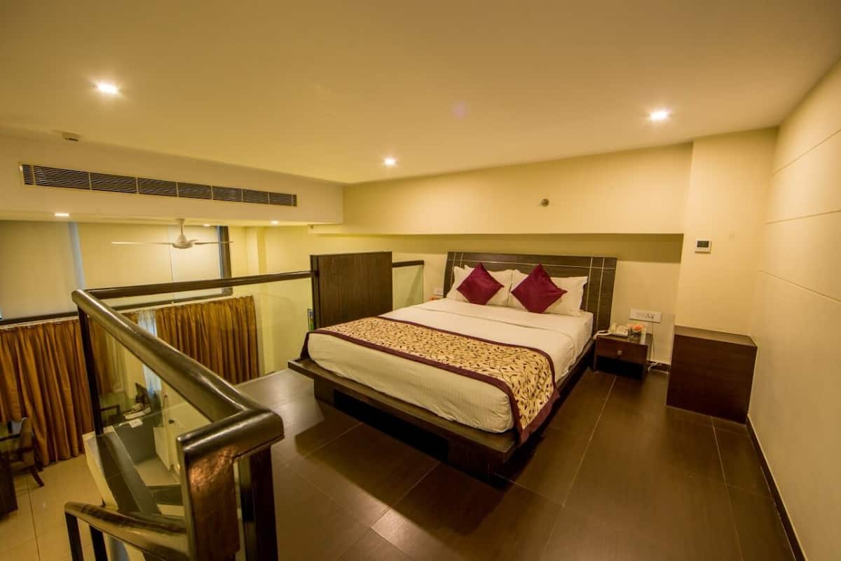 A hotel room with a large bed, a nightstand, a desk, and a view of the outside.