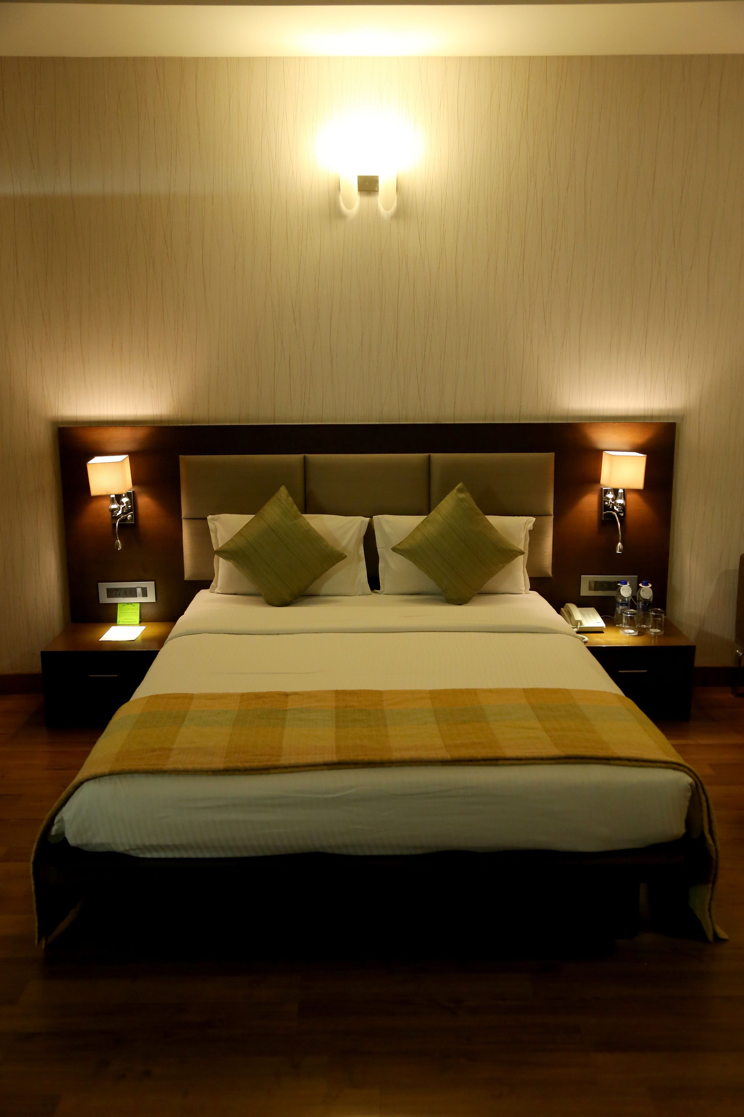 Ein Hotelzimmer mit einem großen Bett, zwei Nachttischen und Wandleuchten.