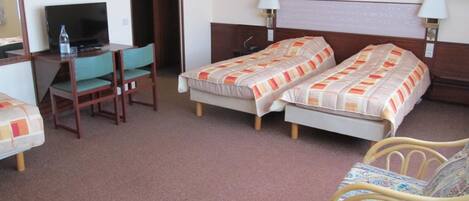 A hotel room with two single beds, a desk with a chair, a television, and two bedside lamps.