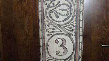 Une porte en bois ornée d’un panneau de verre décoratif, sur lequel figure le chiffre « 3 » et des motifs complexes.