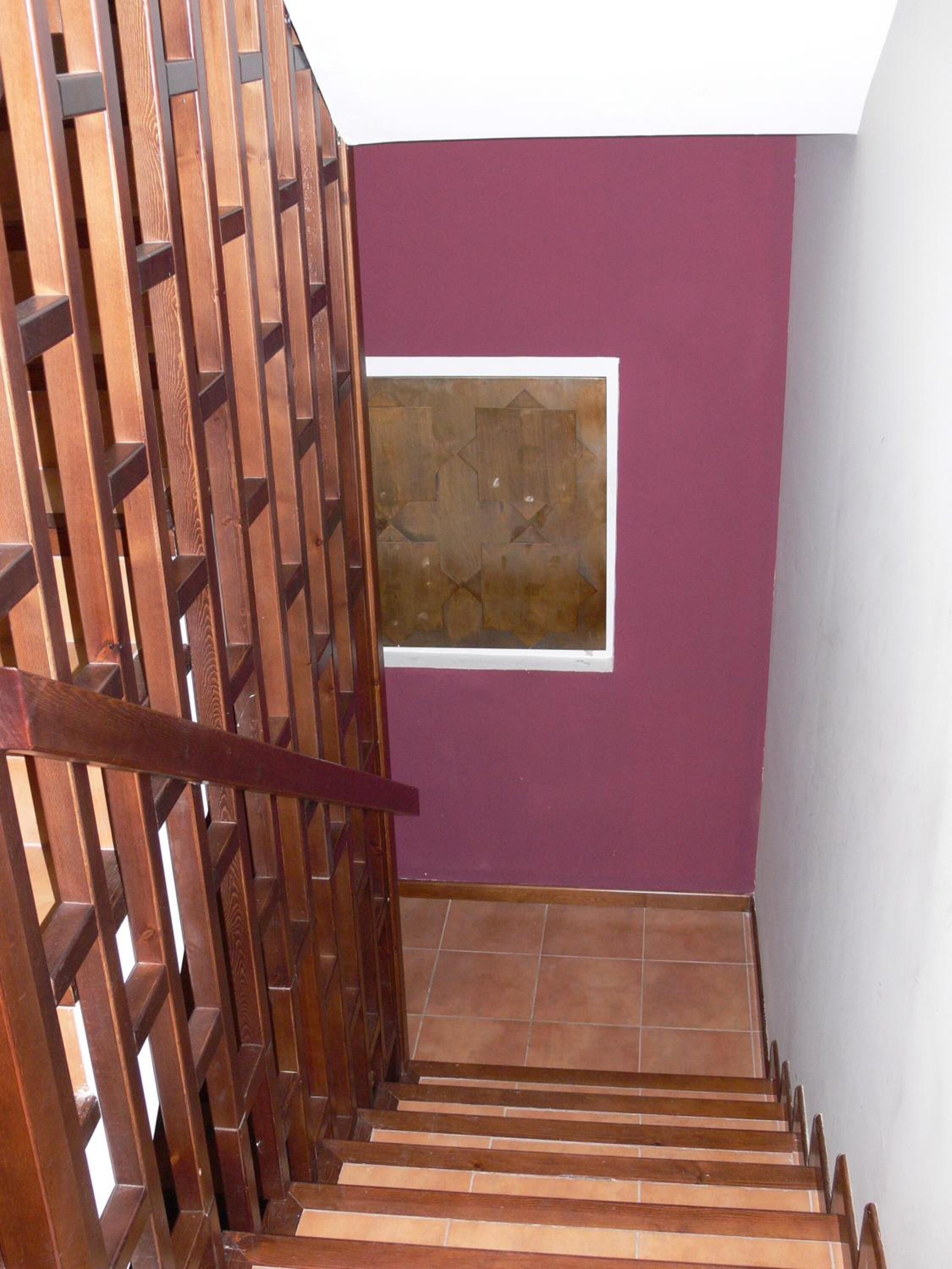 Een houten trap met een paarse muur en een kunstwerk in een lijst.