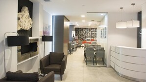 Un área de recepción moderna con un mostrador curvo, zona de estar con sofás y una escultura decorativa en la pared.