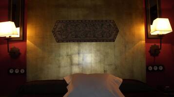 A hotel room with a large bed, two wall-mounted lamps, and a decorative headboard.