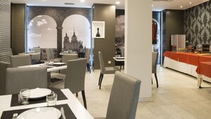 A restaurant with tables set for dining, a buffet area, and a cityscape mural on the wall. - Hotel El Mudayyan (Teruel)