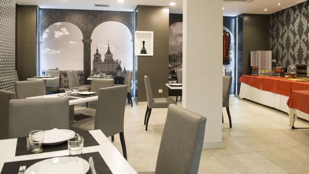 Un restaurante con mesas dispuestas para comer, una zona de bufé y un mural con vista a la ciudad.