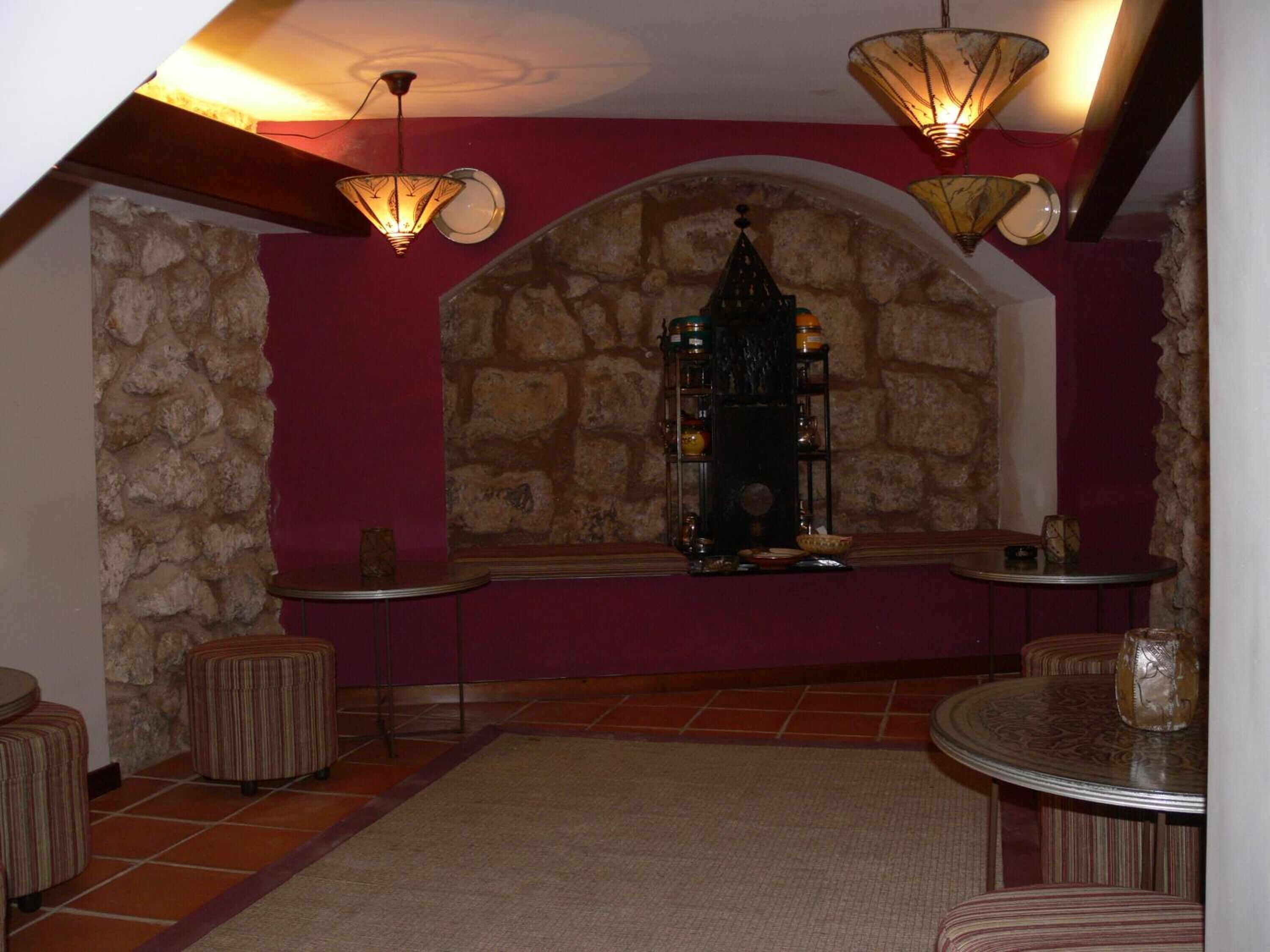 Une pièce chaleureuse avec un mur en pierre, une cheminée et deux petites tables accompagnées de chaises.