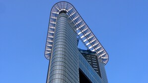 A tall, cylindrical skyscraper with a curved top and a large, open atrium. - The Penthouse (The Hague)