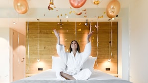 A person sitting on a bed in a room with wooden paneling on the walls. - R hotel experiences (Aywaille)