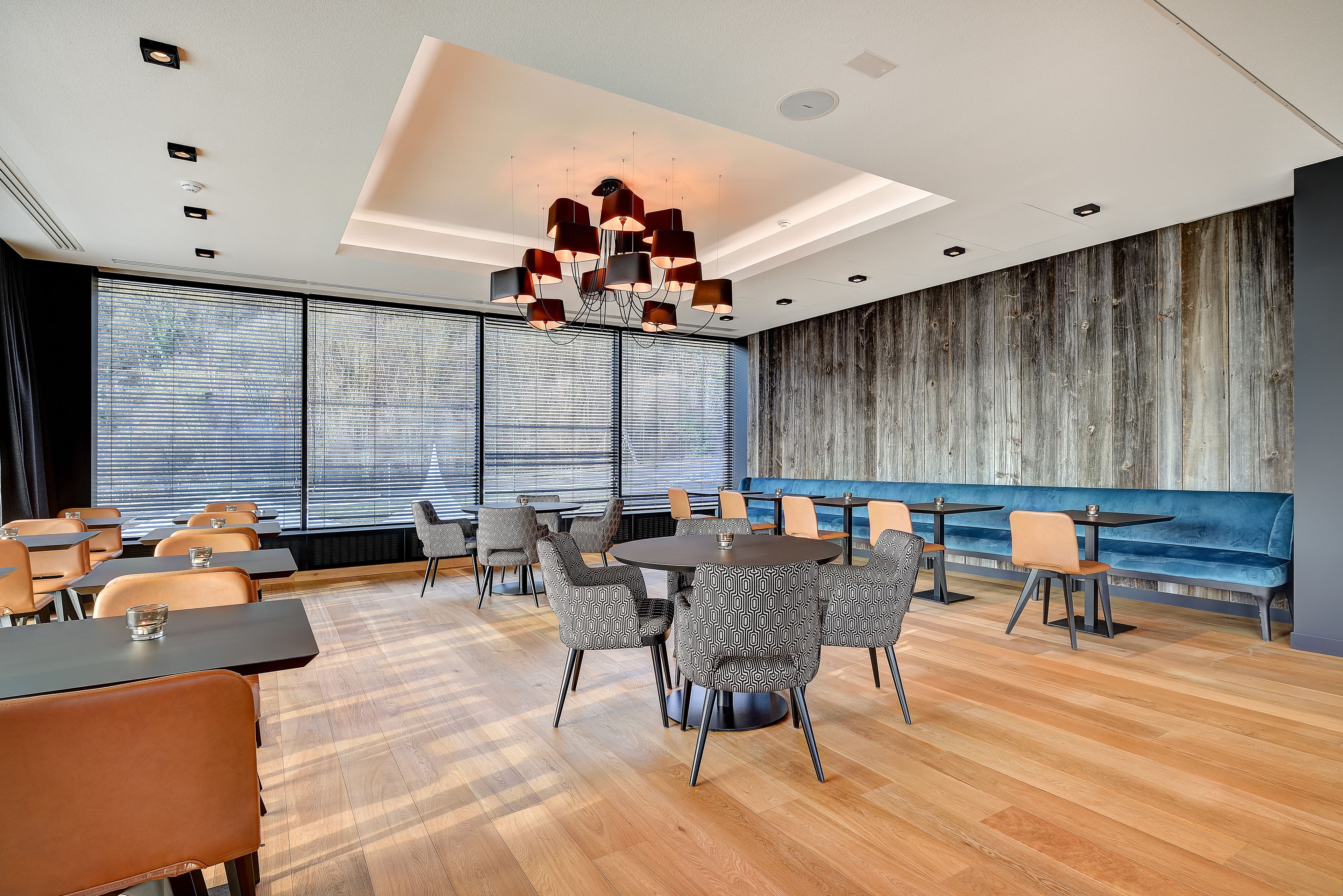 A modern conference room with a large table, patterned chairs, and a unique chandelier.