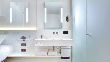 Un baño moderno con un lavamanos blanco, dos espejos y un perchero para toallas.