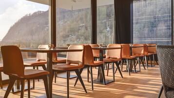A dining area with a view of a mountainous landscape through large windows.