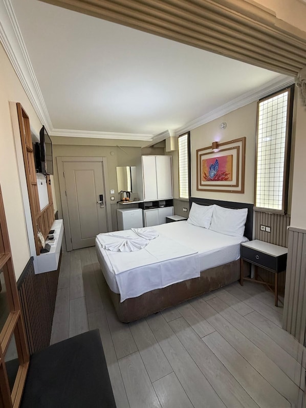 Habitación de hotel con cama, mesita de noche, armario y televisor.