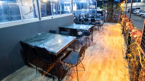 Un comedor interior con mesas y sillas, ventanas amplias y piso de madera.