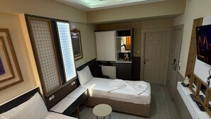 Habitación de hotel con dos camas, un escritorio, una mesita redonda, un televisor y un armario.