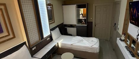 A hotel room with two beds, a desk, a small round table, a TV, and a wardrobe.