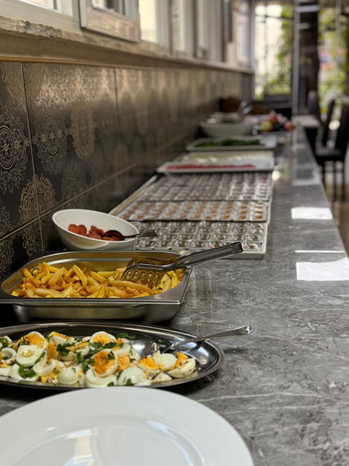 A buffet setup with various dishes including fries, eggs, and a salad.
