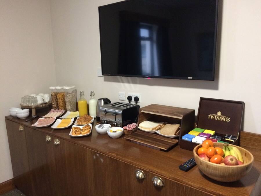 A breakfast buffet with various food items, a toaster, and a box of Twinings tea.