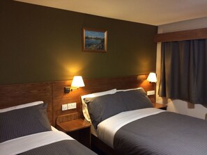 A hotel room with two beds, wooden headboards, and wall-mounted lamps. - Crosshill House (Glasgow)
