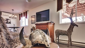A living room with a television, a fireplace, and a decorative deer statue. - Auberge Motel Drakkar (Shawinigan)