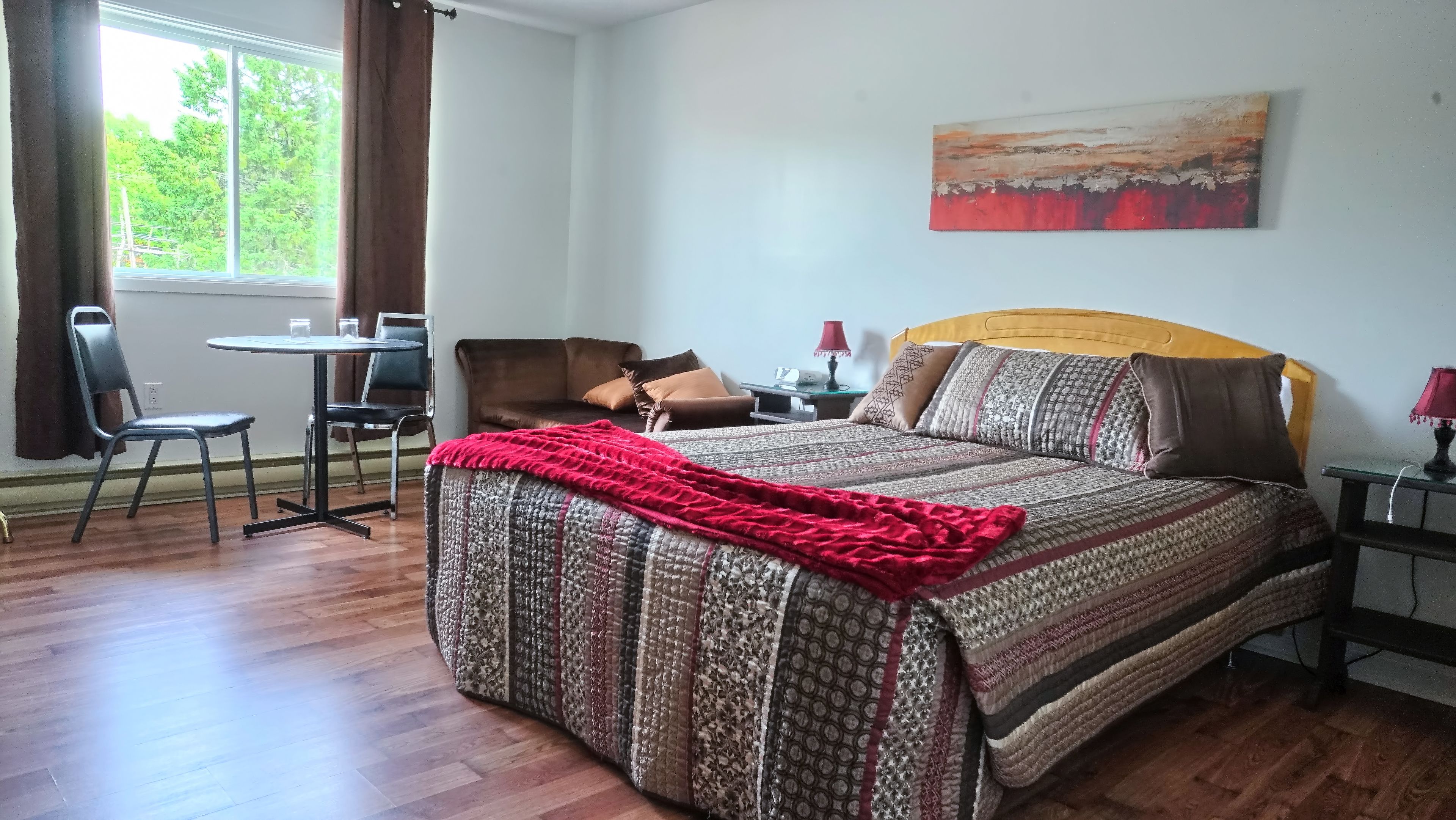 Un dormitorio con cama, escritorio, silla y ventana.