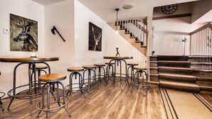 A modern interior with wooden flooring, a staircase, and multiple bar stools arranged around a central table. - Auberge Motel Drakkar (Shawinigan)