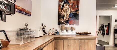 Une cuisine avec des meubles en bois, une machine à café et un grand tableau accroché au mur.