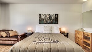 A bedroom with a bed, a nightstand, a dresser, and a wall-mounted artwork. - Auberge Motel Drakkar (Shawinigan)