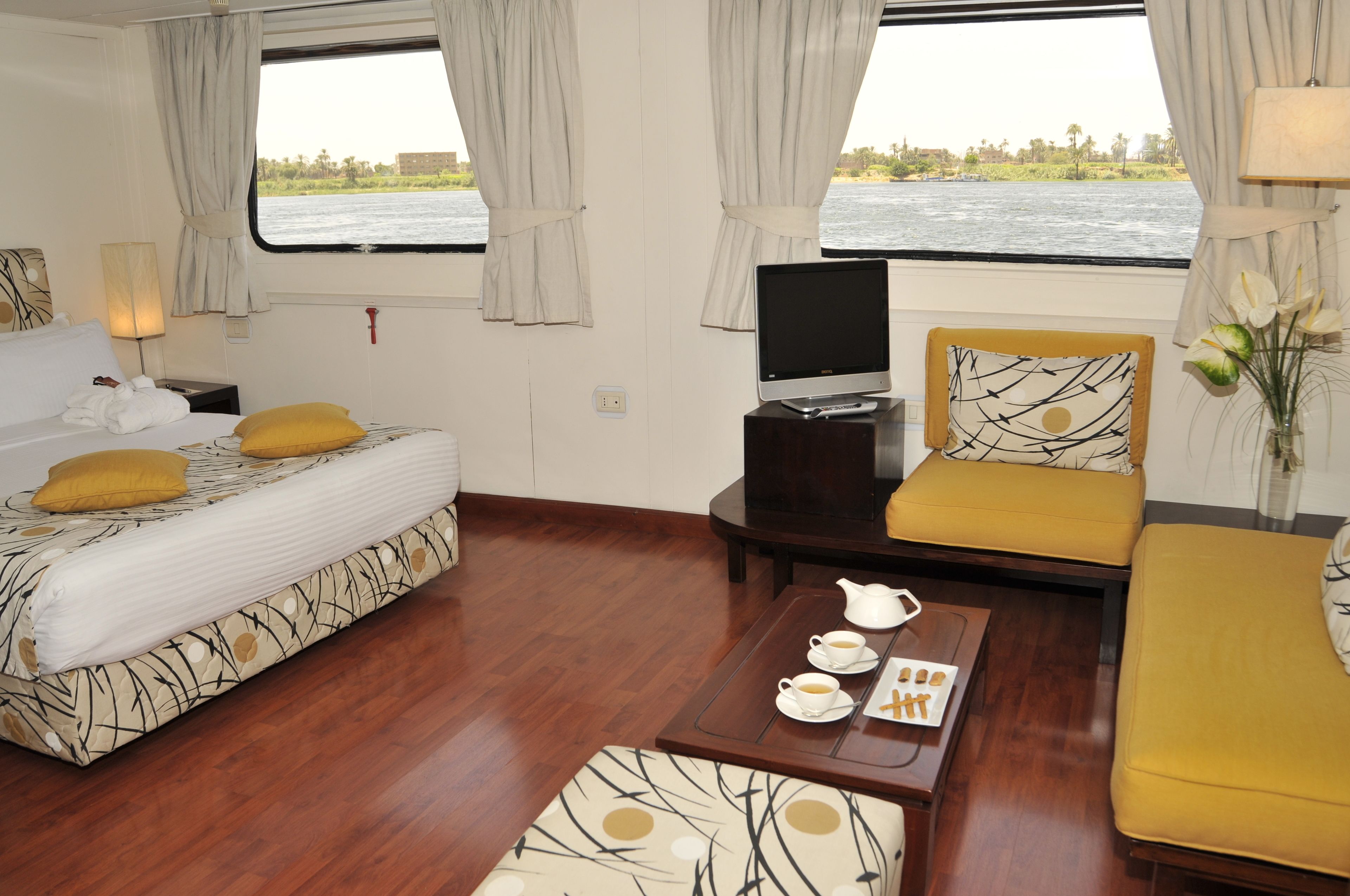 A room with a bed, a sofa, a TV, and a table with a teapot and cups.