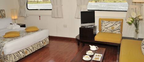 A room with a bed, a sofa, a TV, and a table with a teapot and cups.