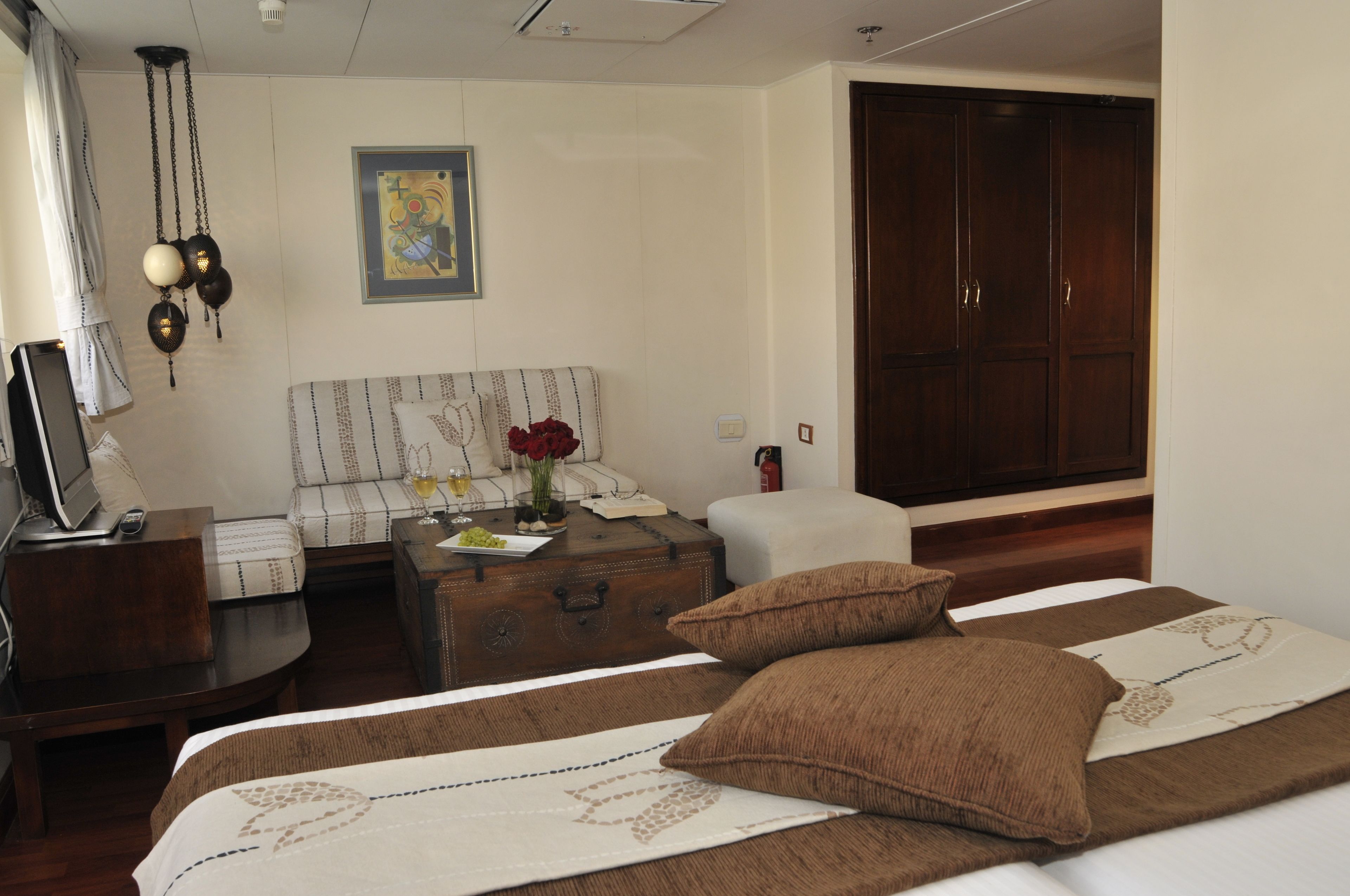 A hotel room with a bed, a sofa, a desk with a computer, a suitcase, and a wardrobe.