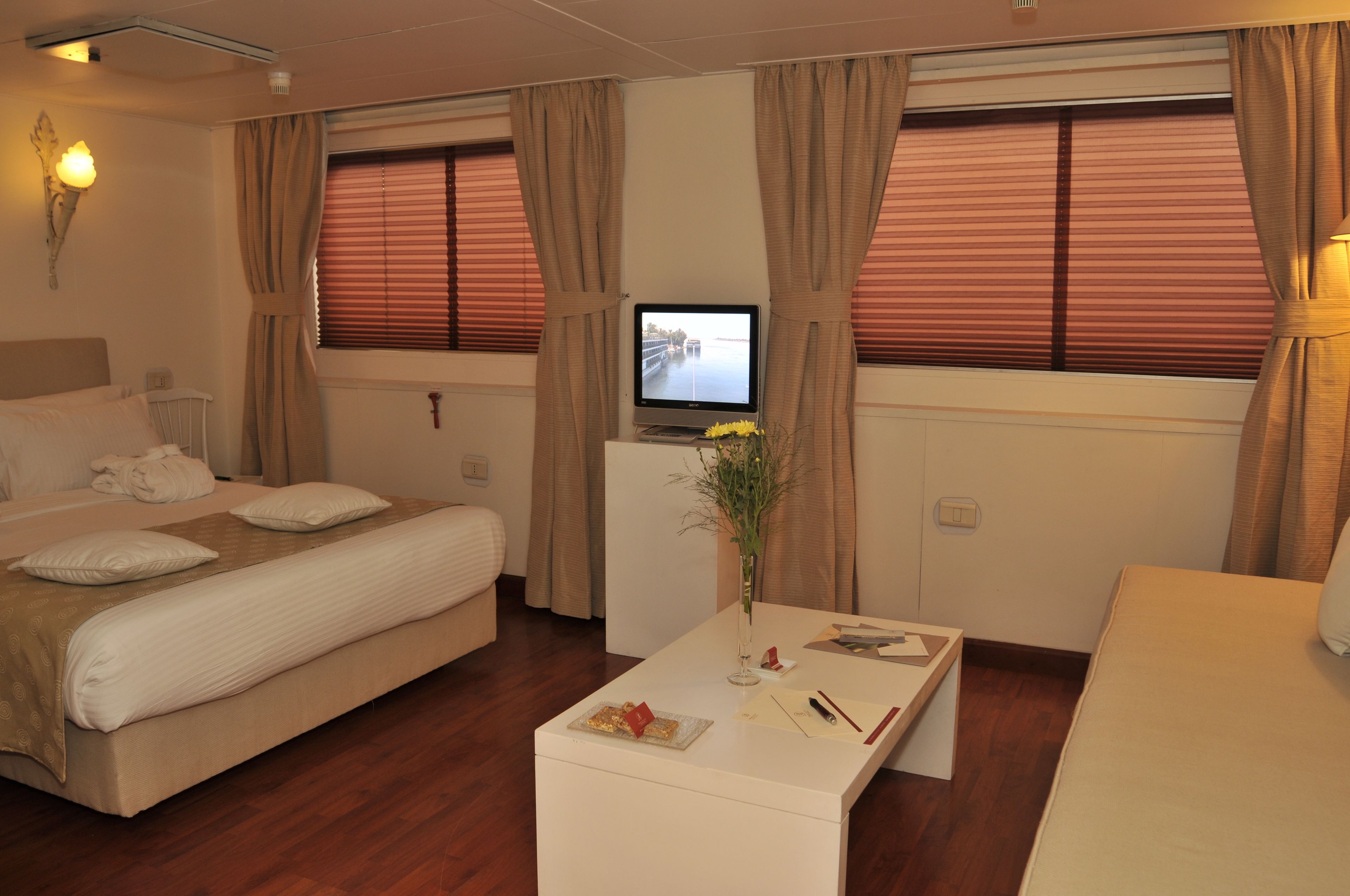 A hotel room with a bed, a desk, a TV, and curtains.