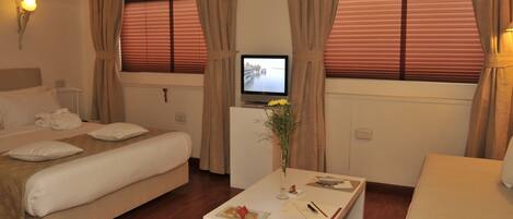 A hotel room with a bed, a desk, a TV, and curtains.