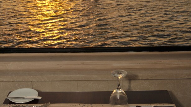 Mesa para dos con vista a veleros en el agua al atardecer.