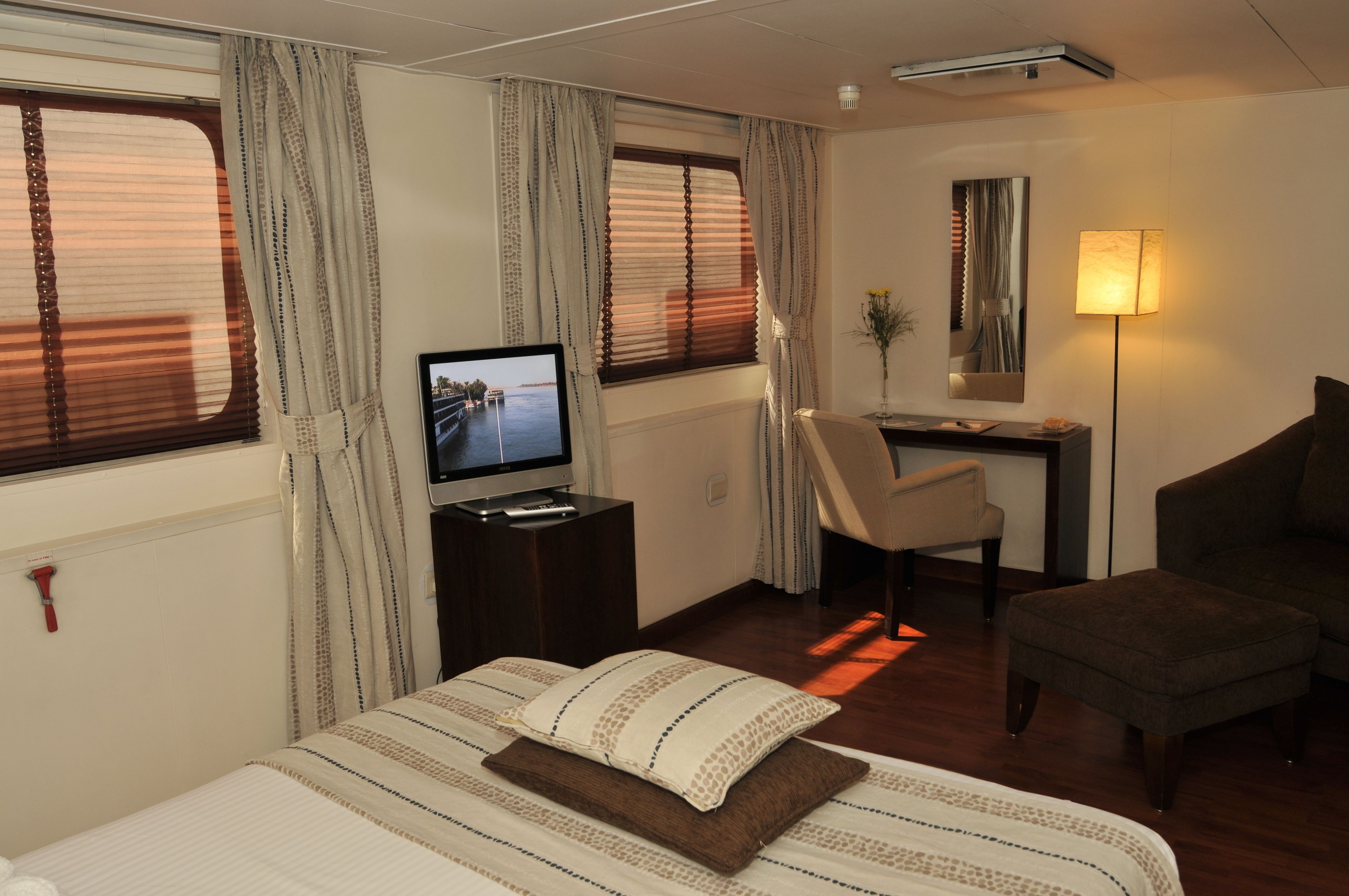 Een hotelkamer met een bed, een bureau, een stoel, een televisie en een lamp.