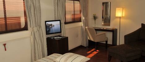 Een hotelkamer met een bed, een bureau, een stoel, een televisie en een lamp.