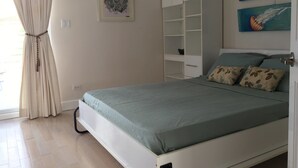A bedroom with a bed, a wardrobe, and two paintings on the wall. - Villa 415A at Jolly Harbour (Jolly Harbour)