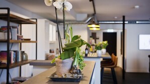 Una cocina moderna con una isla central, una estantería y un comedor con sillas.