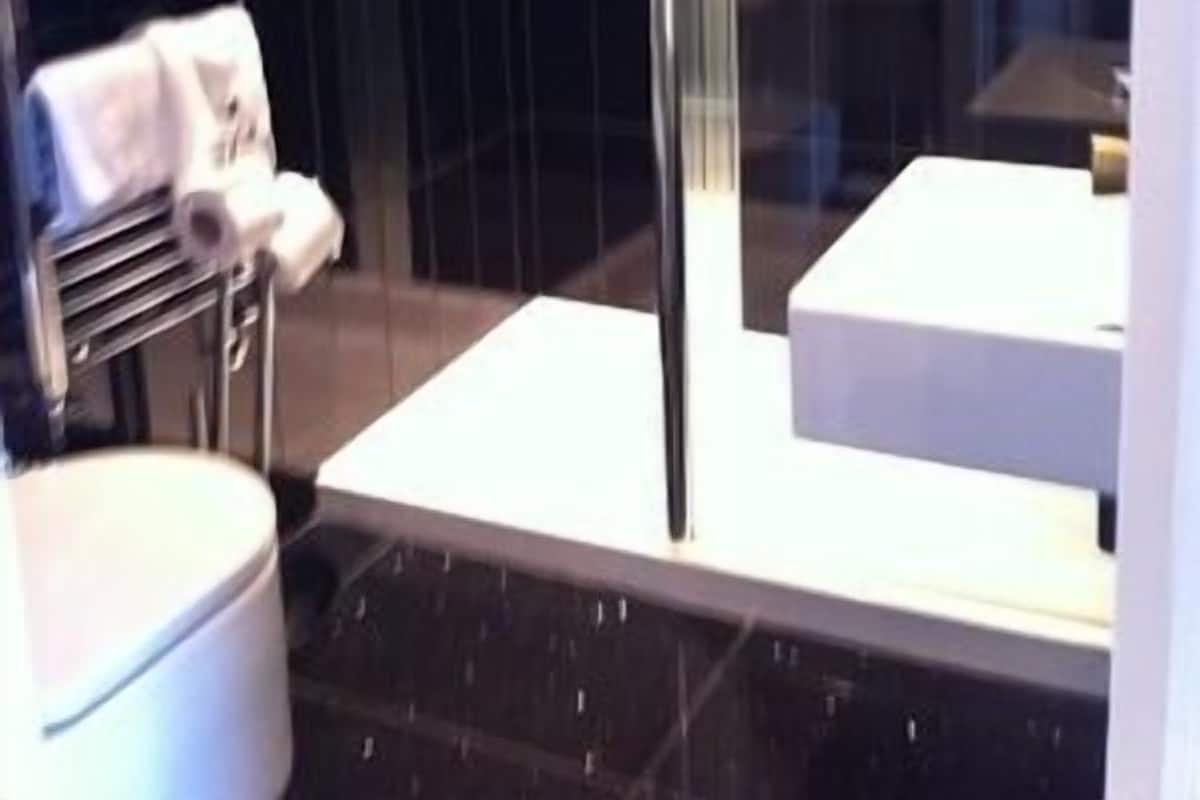 A modern bathroom with a glass shower enclosure, a white sink, and a towel rack with neatly folded towels.