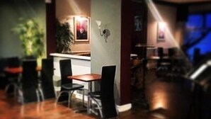 A restaurant with a wooden floor, a counter, and black chairs. - The Lilly (Llandudno)