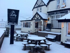 A snow-covered outdoor seating area with tables and benches at The Lilly Restaurant. - The Lilly (Llandudno)