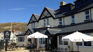 A building with a pub bar, outdoor seating, and a sign for 'The Lilly Restaurant'. - The Lilly (Llandudno)