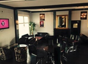 A conference room with a large table, multiple chairs, a potted plant, and framed pictures on the walls. - The Lilly (Llandudno)