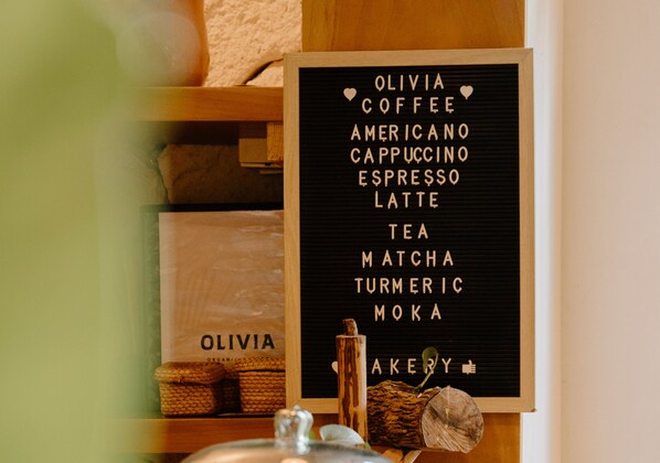 A sign listing coffee and tea options at Olivia Coffee.